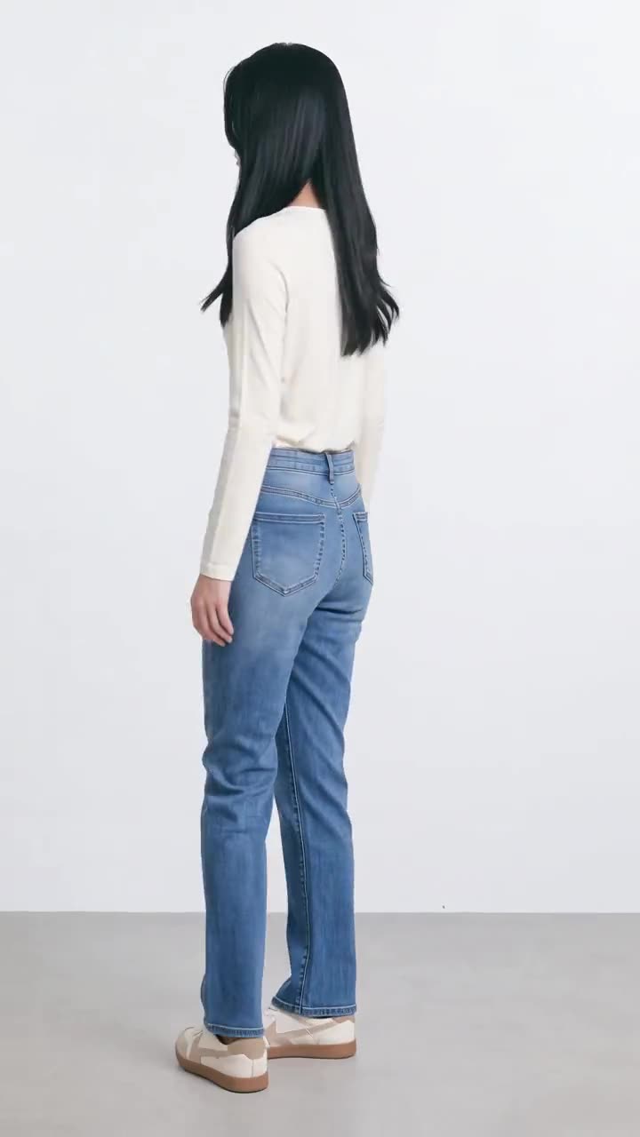 A model turned away from the camera, showing the back of a cream top and blue jeans